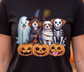 A close-up of a black short-sleeve T-shirt worn by a person, featuring a colorful graphic print of four cute dogs dressed in Halloween costumes with pumpkins below them.