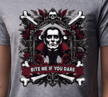 A close-up of a gray heather t-shirt featuring a graphic print of a vampire with a skull and crossbones, red roses, and the text 'BITE ME IF YOU DARE'.