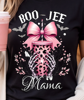 A close-up of a person wearing a black graphic T-shirt with the words “BOO-JEE Mama” and a pink leopard-print drink cup design, while holding a pink takeaway coffee cup.
