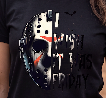 A close-up of a person wearing a black graphic t-shirt. The shirt features a split design: the left half shows a distressed hockey mask in white, black, and red, while the right half displays the text 'I WISH IT WAS FRIDAY' in a dripping horror font.