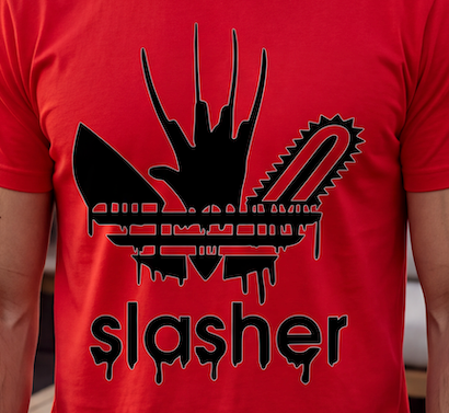 A close-up of a person wearing a bright red t-shirt with a black graphic print. The graphic features a stylized hand with three fingers, a chainsaw blade, and the word 'slasher' in a dripping font below.