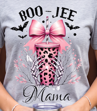 A close-up of a person wearing a heather gray graphic t-shirt. The shirt features a Halloween-themed design with the text 'BOO-JEE Mama', a pink leopard-print tumbler cup with a large pink bow, skeleton hands, bats, and pink leaves.