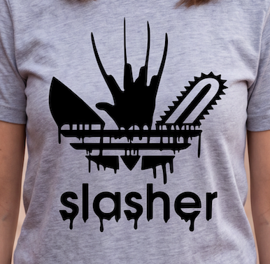 A close-up of a person wearing a heather gray t-shirt with a black graphic print. The graphic is a stylized Adidas trefoil logo where the leaves are replaced by a dripping chainsaw and a dripping knife, with the word 'slasher' printed below in a dripping font.