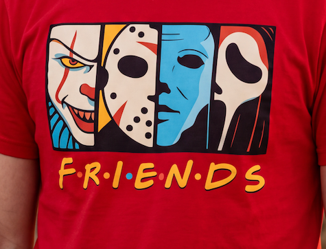 A close-up of a person wearing a red t-shirt with a graphic print of horror movie villains styled like the Friends logo, featuring the word 'FRIENDS' in yellow with red and blue dots.