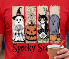 A close-up of a red t-shirt featuring a Halloween graphic with four vertical panels showing a ghost, a pumpkin, a black cat, and a tombstone, with the text 'Spooky Sea'. A hand holding a coffee cup is visible in the lower right corner.