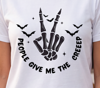 A close-up of a white short-sleeve T-shirt worn by a person, featuring a black graphic of a skeletal hand making the rock on gesture, surrounded by bats, stars, and the text 'PEOPLE GIVE ME THE CREEEP'.
