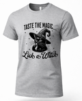 A light gray heather crewneck t-shirt featuring a black graphic print of a witch cat wearing a pointed hat, with the text 'TASTE THE MAGIC.