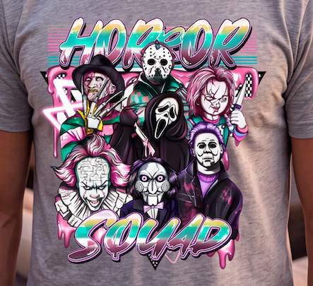 A person wearing a heather gray t-shirt with a colorful graphic print of various horror movie characters and the words 'HORROR SQUAD' in a stylized neon font.