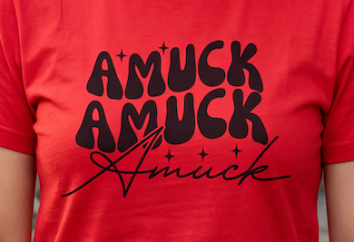 A red close up short-sleeve crewneck t-shirt with a black graphic print on the front reading 'AMUCK AMUCK Amuck' in stylized lettering, displayed on a clean white background.