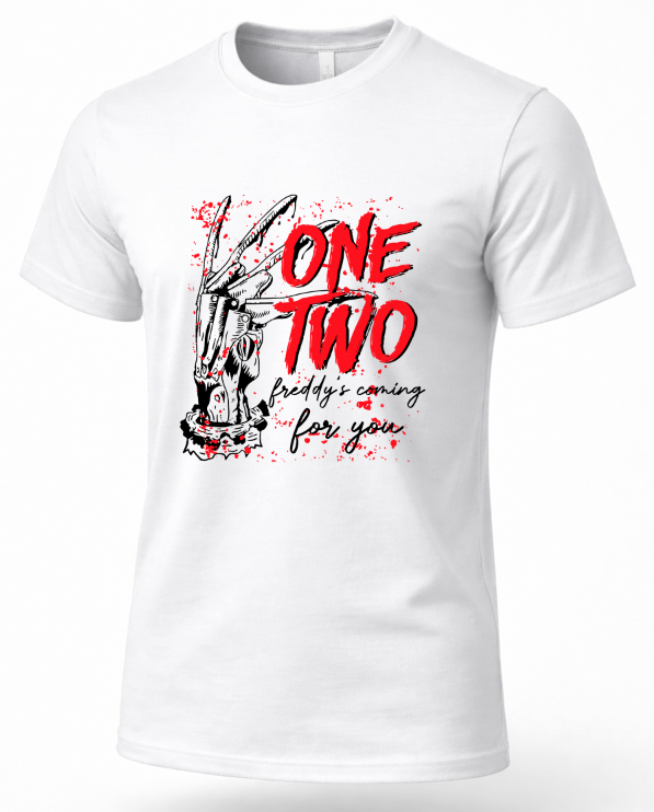 A white short-sleeve crewneck t-shirt with a graphic print on the front. The graphic features a black and white illustration of a hand holding a knife, with the words 'ONE TWO' in bold red letters and 'freddy's coming for you' in black script below, set against a red paint splatter background.