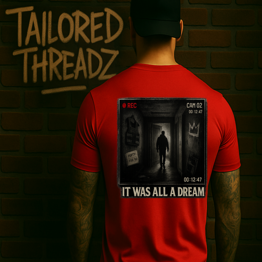 Back of a red streetwear graphic tee by Tailored Threadz showing a vintage camcorder-style hallway design, photographed against a dark brick wall for product display.