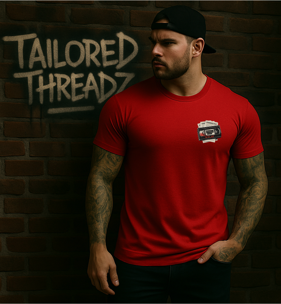 Model wearing a red Tailored Threadz graphic tee featuring a small chest design, photographed in front of a brick wall with Tailored Threadz branding.