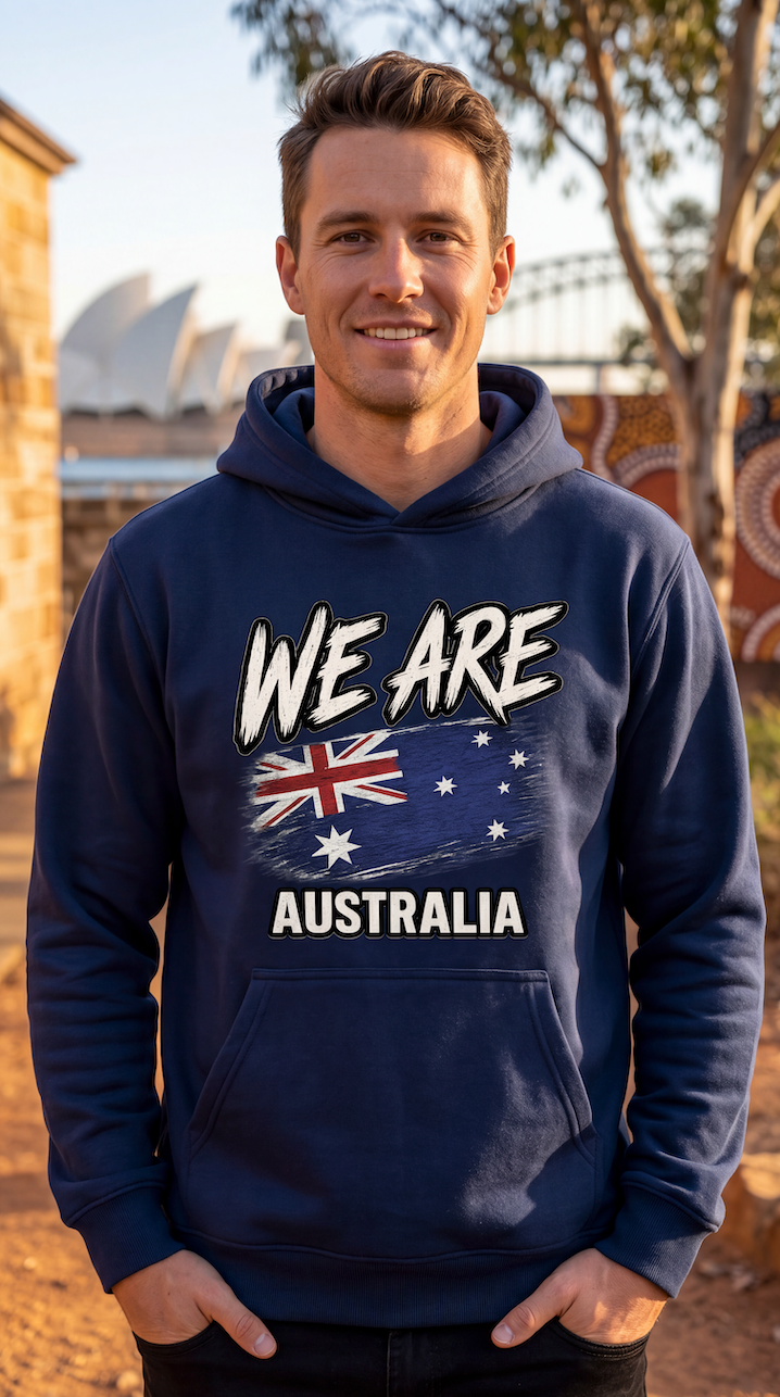 A man wearing a navy blue hoodie with a graphic that reads 'WE ARE AUSTRALIA' and features the Australian flag, standing outdoors in front of Sydney Opera House and trees.