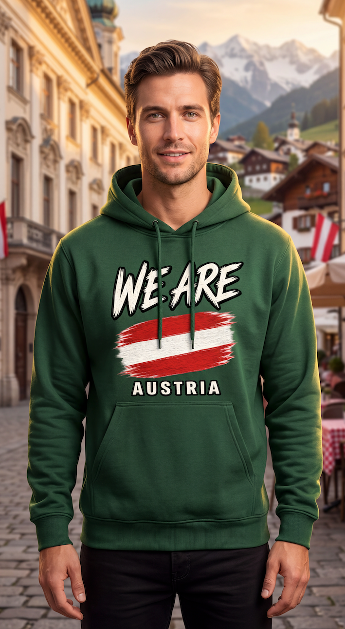 A man wearing a dark green hoodie with a graphic print that reads 'WE ARE AUSTRIA' and features the Austrian flag, set against a blurred background of a European town and mountains.