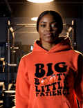 Woman wearing orange “Big Booty Little Patience” hoodie in a gym setting