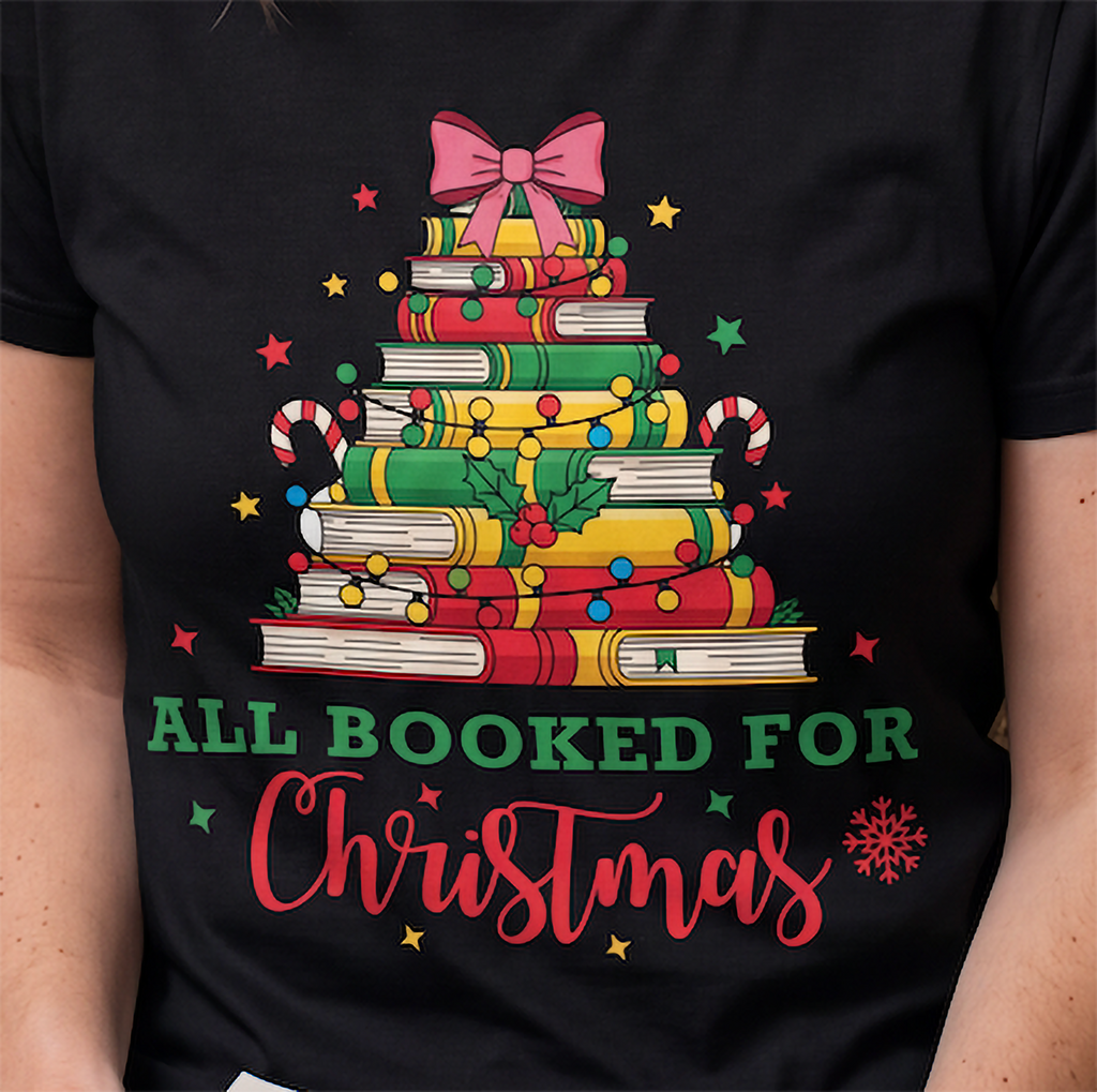 Close-up of black All Booked for Christmas shirt featuring festive books, Christmas lights, candy canes and holiday accents.