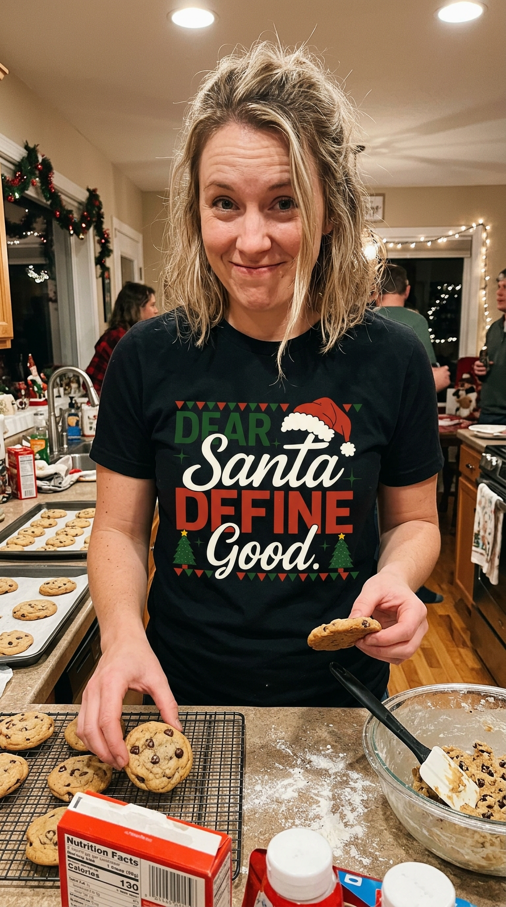Lifestyle – Black: Woman wearing a black Dear Santa Define Good Christmas graphic t-shirt while preparing holiday food in a festive kitchen.