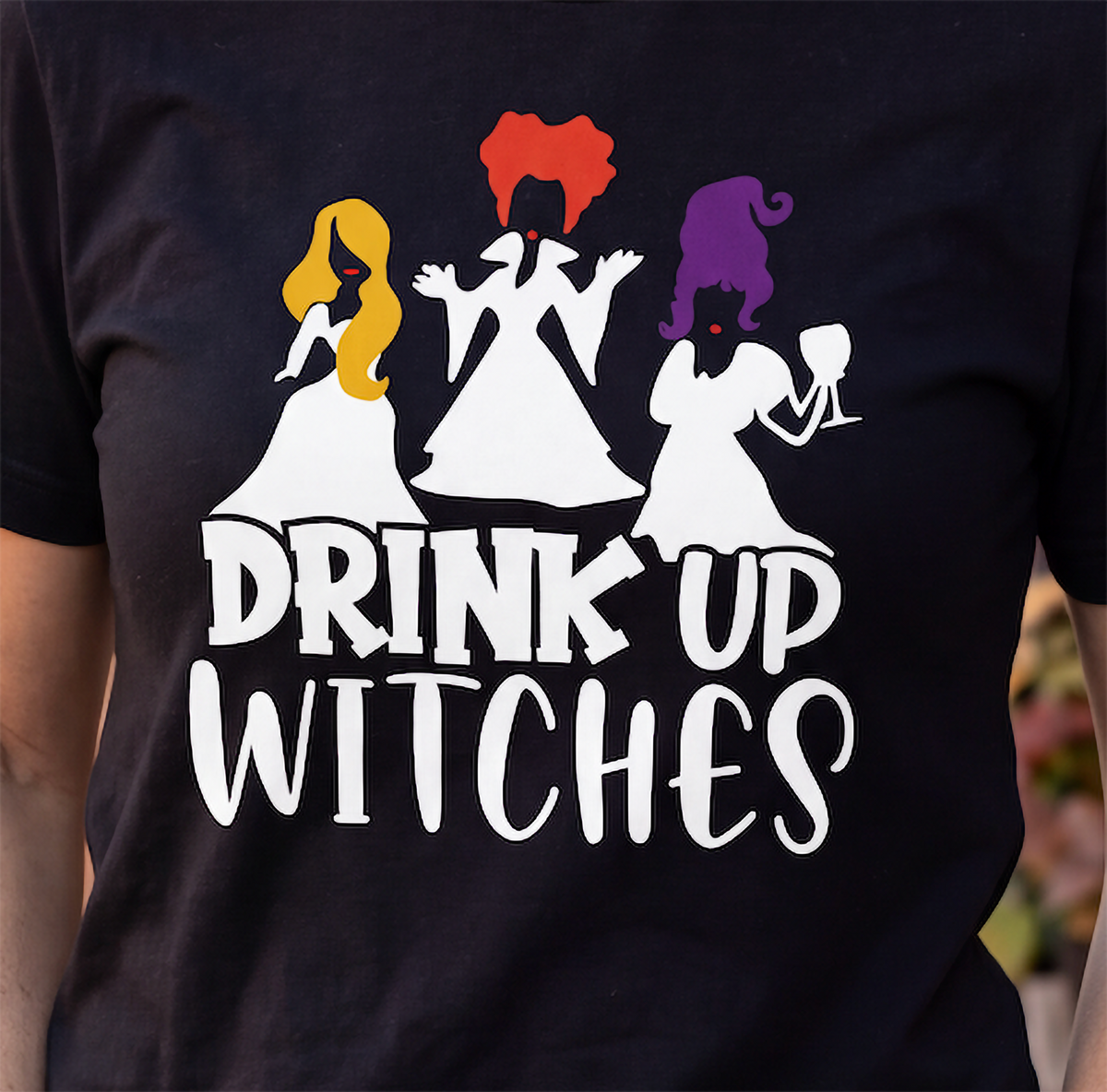 Close-up of black Drink Up Witches Halloween shirt with colorful witch design