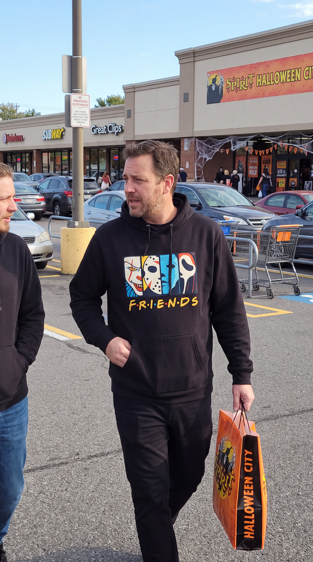 Man wearing black Horror Friends hoodie with colorful slasher character graphic for Halloween.