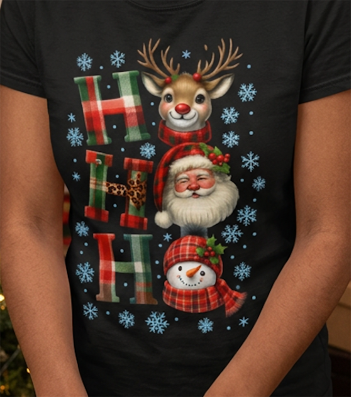 Close-up of black Christmas shirt showing colorful Ho Ho Ho design with reindeer, Santa, snowman and blue snowflakes.