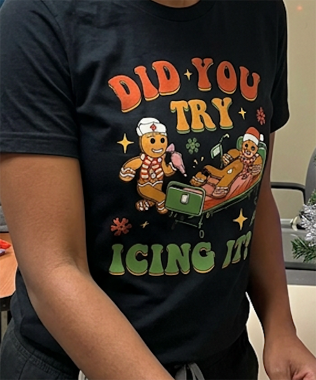 Close-up of funny gingerbread icing Christmas shirt on black fabric, featuring a festive healthcare joke.