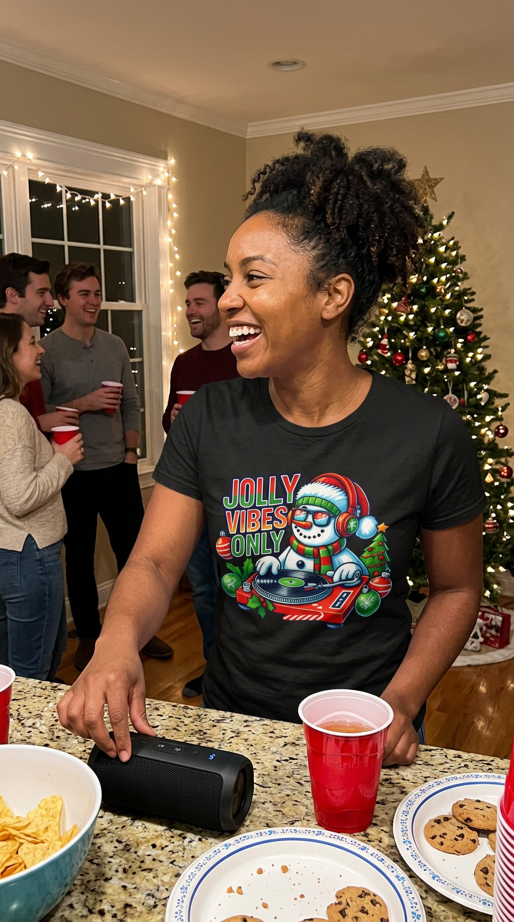 Black Lifestyle: Woman wearing a black Jolly Vibes Only Christmas t-shirt featuring a festive snowman DJ with headphones, sunglasses, Christmas ornaments, and a turntable.
