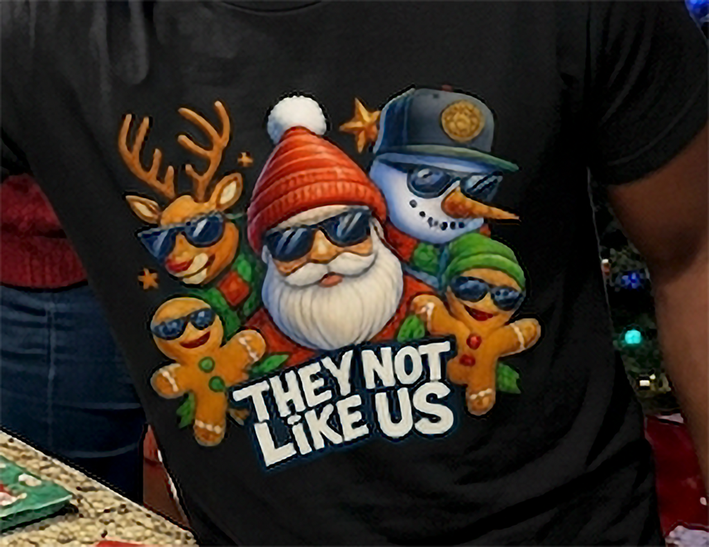 Black Close-Up: Close-up of colorful They Not Like Us Christmas graphic printed on a black shirt, featuring Santa and festive holiday characters in sunglasses.