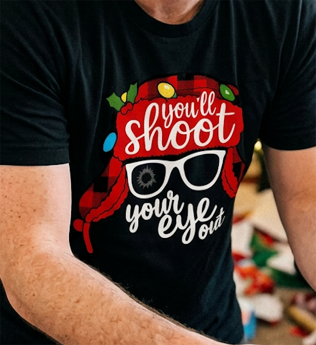 Close-up of black Christmas movie quote t-shirt showing red winter hat, holiday lights and You'll Shoot Your Eye Out design