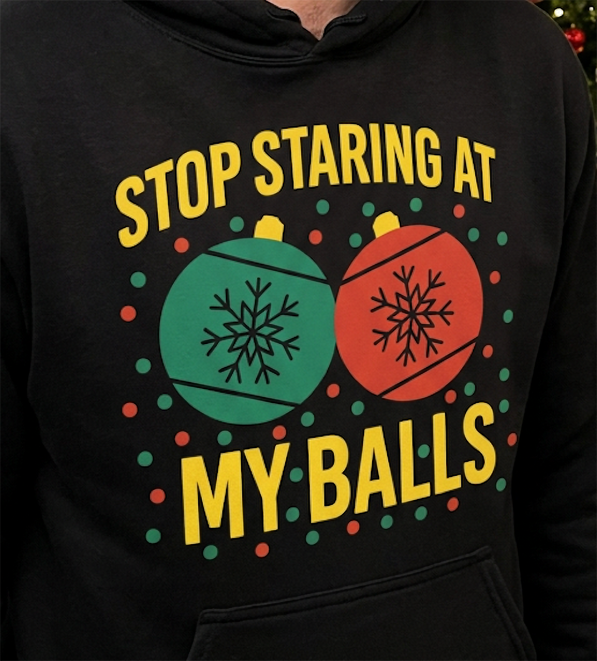 Close-up of Stop Staring at My Balls Christmas ornament graphic on black hoodie