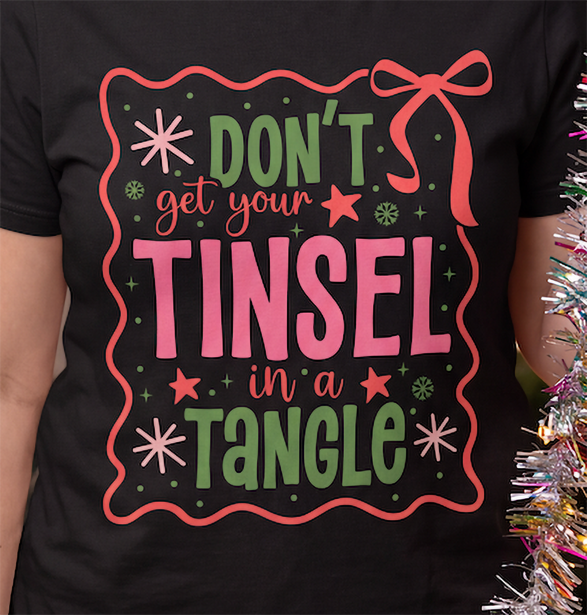 Close-up of Don’t Get Your Tinsel in a Tangle retro Christmas graphic on a black T-shirt.