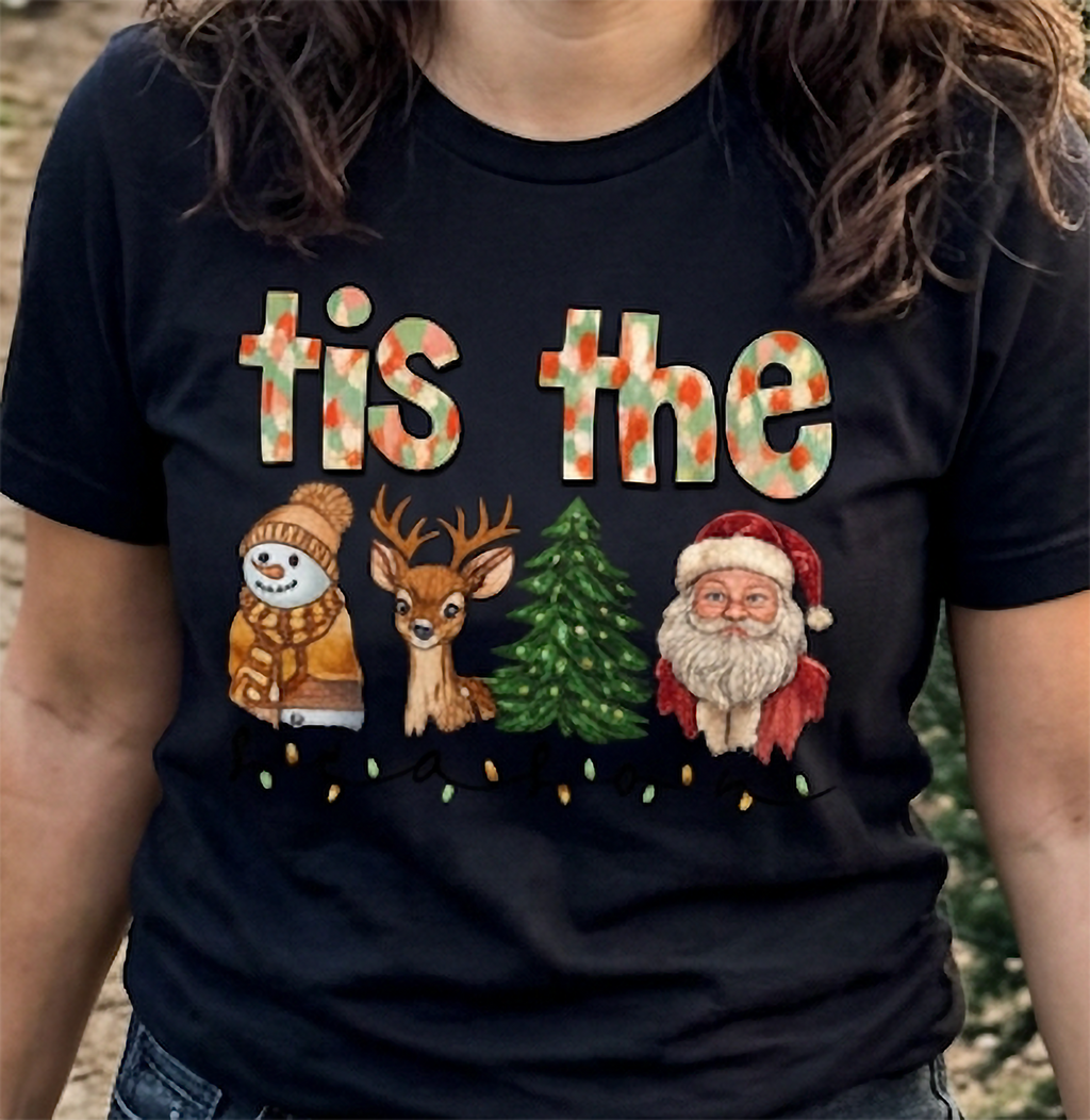 Close-up of black Tis the Season Christmas shirt highlighting colorful holiday characters, festive lettering, and Christmas lights.