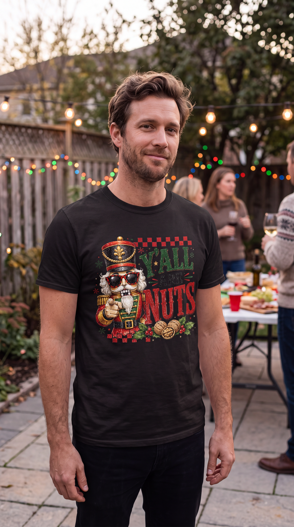 Man wearing black Y’all Are Nuts nutcracker Christmas graphic shirt outdoors during the holiday season.
