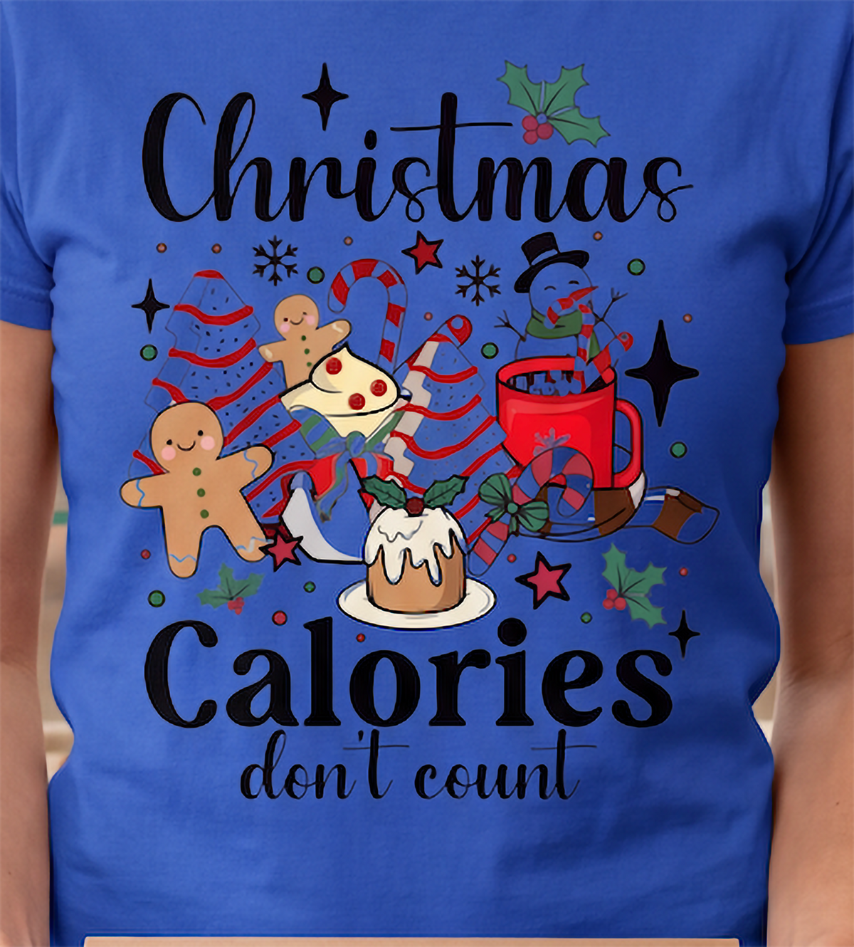 Close-up of royal blue Christmas Calories Don’t Count shirt featuring colorful festive food artwork.