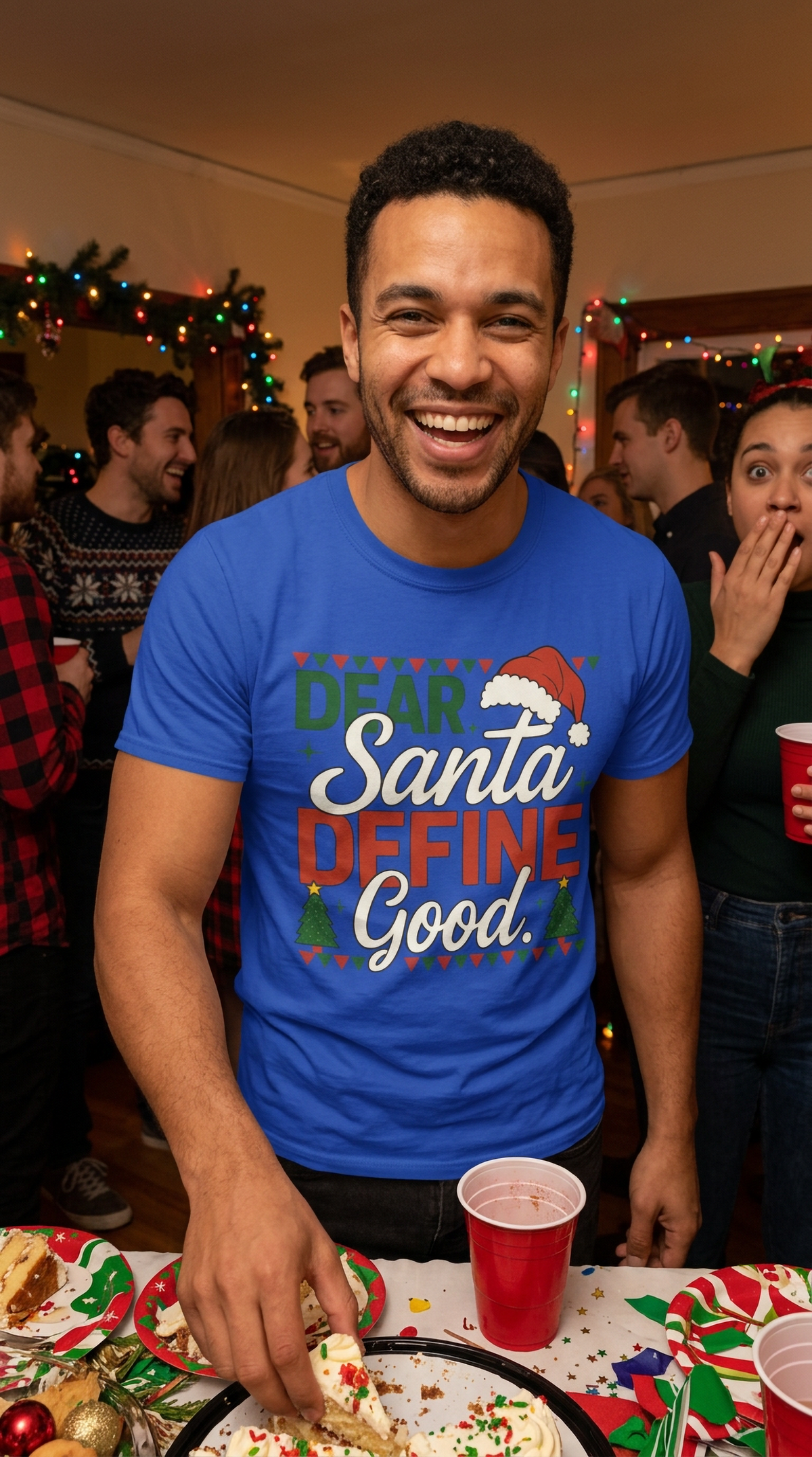 Lifestyle – Blue: Man wearing a blue Dear Santa Define Good Christmas graphic t-shirt at a festive indoor holiday gathering.