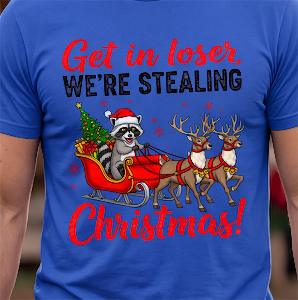Close-up of Get in Loser We’re Stealing Christmas raccoon and reindeer graphic printed on a blue T-shirt.