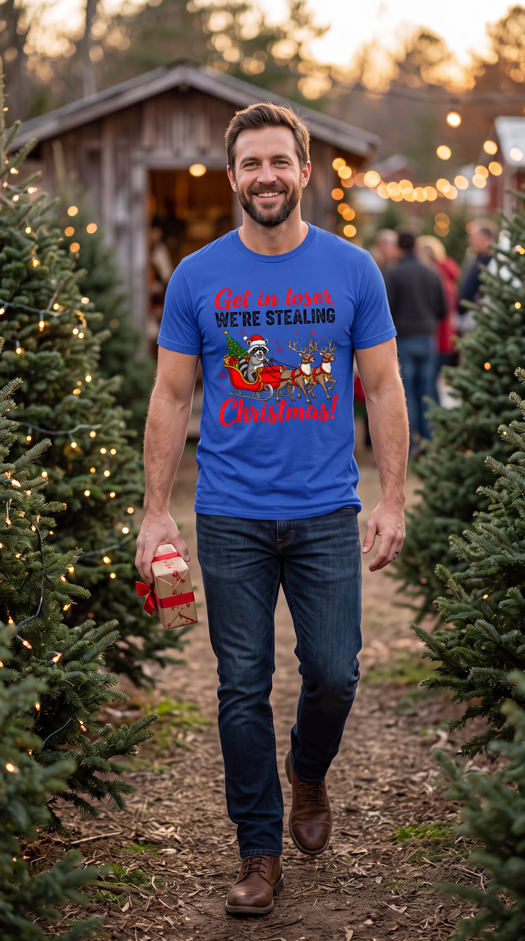 Man wearing a blue Get in Loser We’re Stealing Christmas shirt outdoors during the holiday season