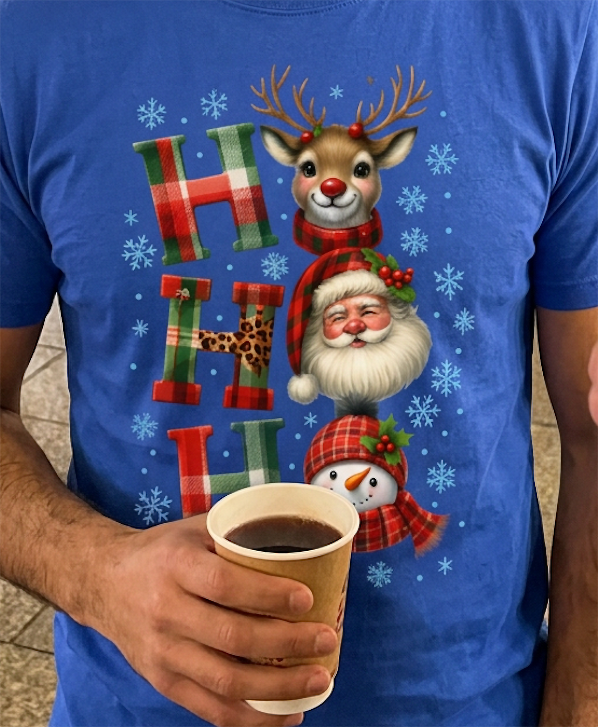Close-up of blue Christmas t-shirt showing festive Santa Claus, reindeer and snowman graphic with winter snowflakes.