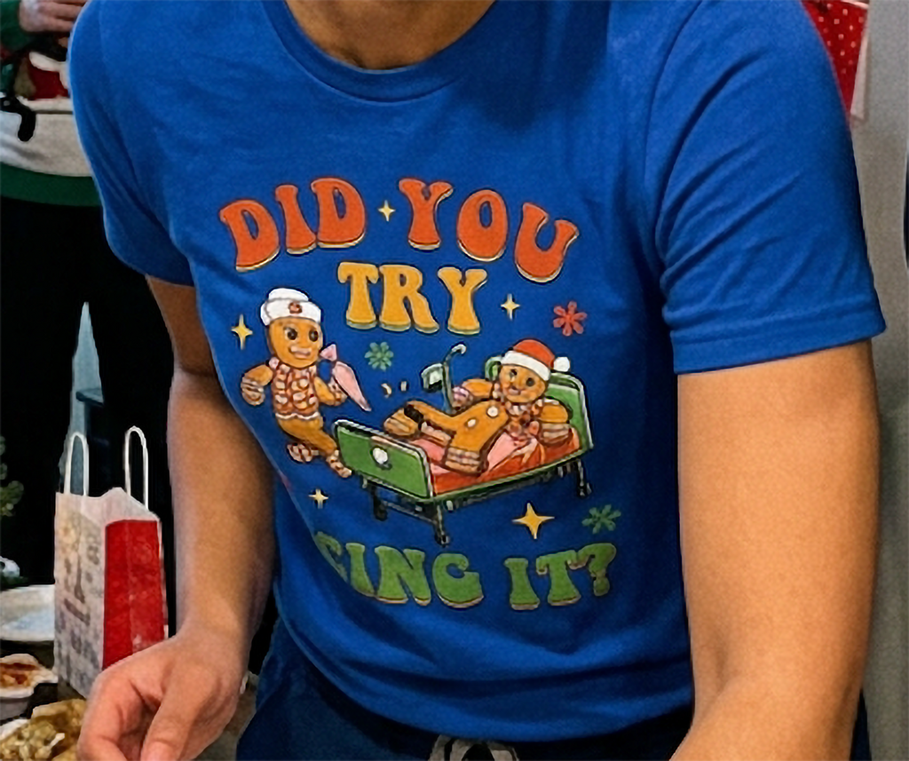 Close-up of funny Christmas gingerbread icing graphic printed on a blue unisex t-shirt.