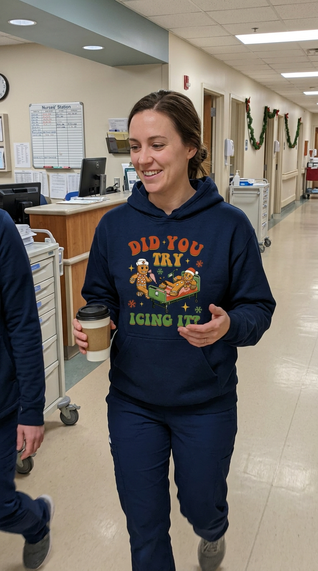 Woman wearing navy blue Did You Try Icing It gingerbread Christmas hoodie in a hospital