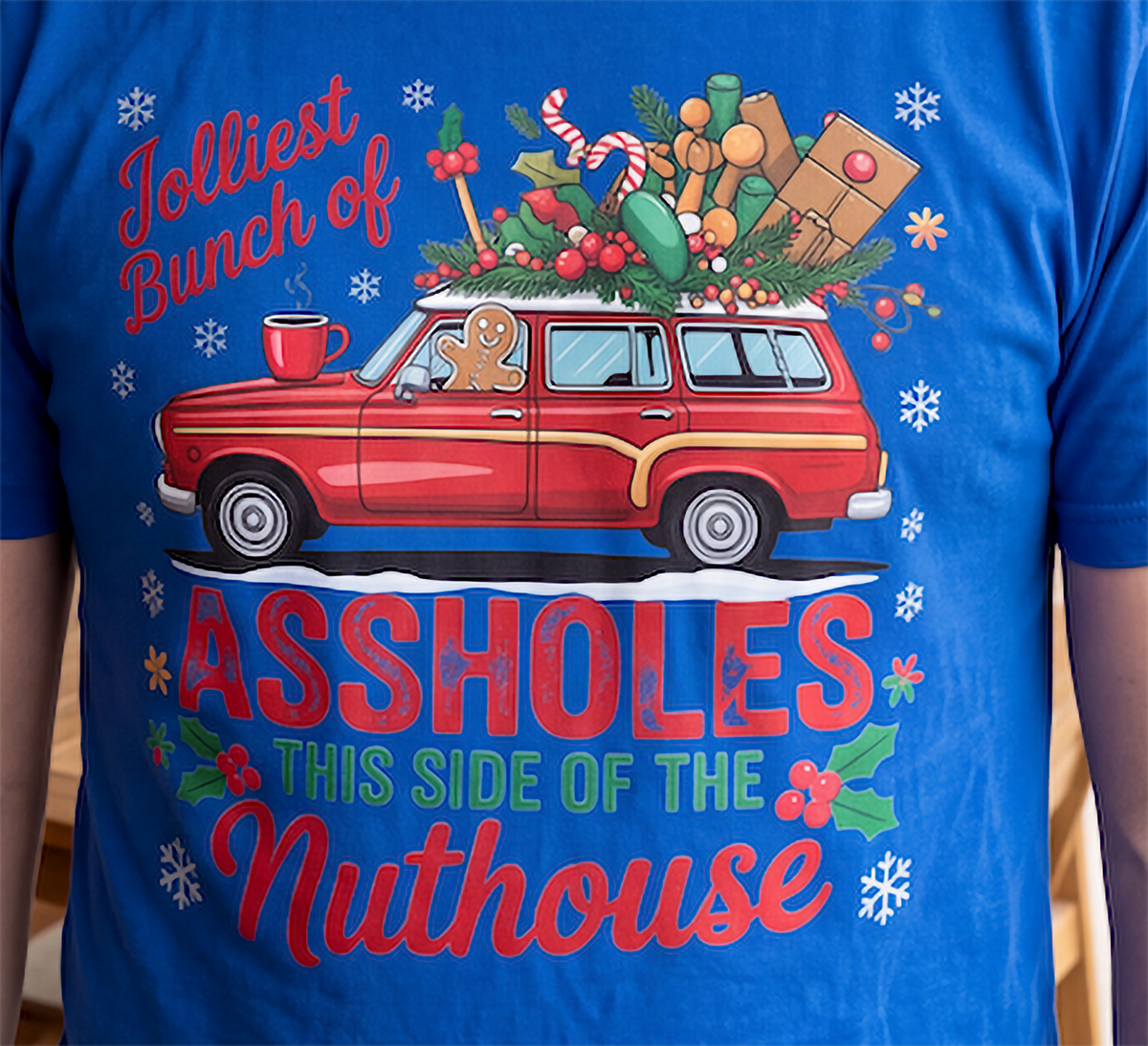 Close-up of Jolliest Bunch of Assholes Christmas graphic printed on blue shirt.