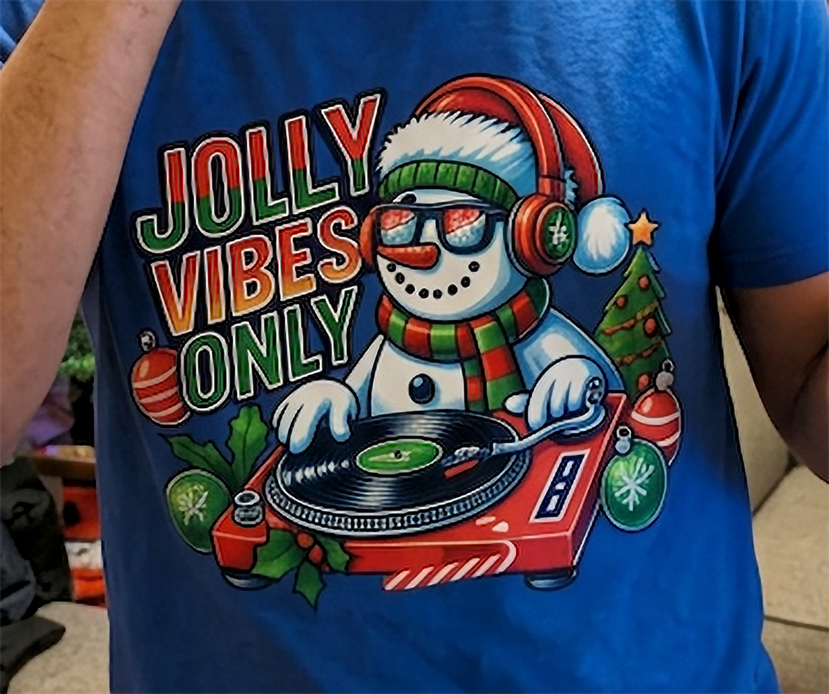 Blue Close-Up: Close-up of Jolly Vibes Only snowman DJ Christmas artwork on a blue t-shirt.