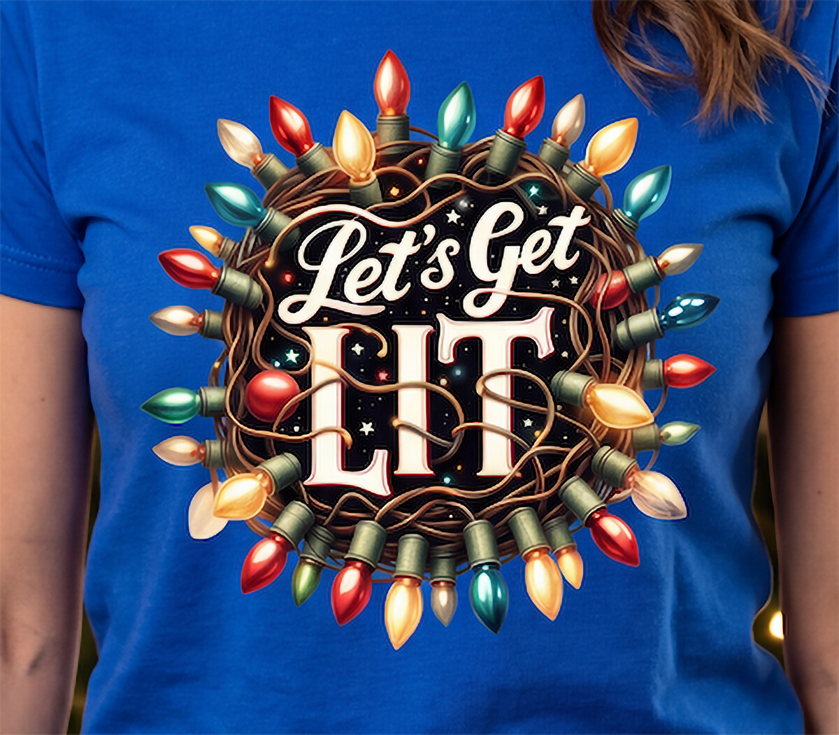 Close-up of Let’s Get Lit Christmas lights graphic printed on blue shirt.
