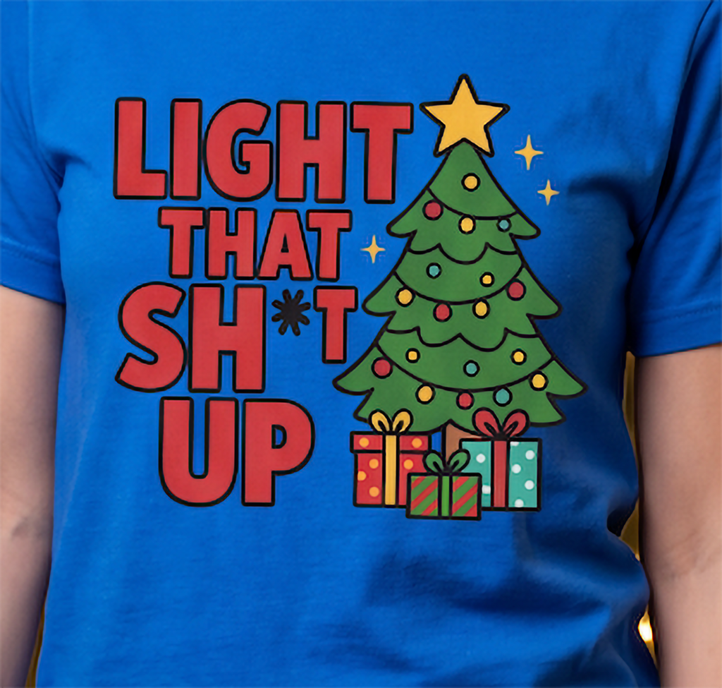 Close-up of royal blue Light That Shit Up Christmas shirt with colorful Christmas tree and presents graphic.