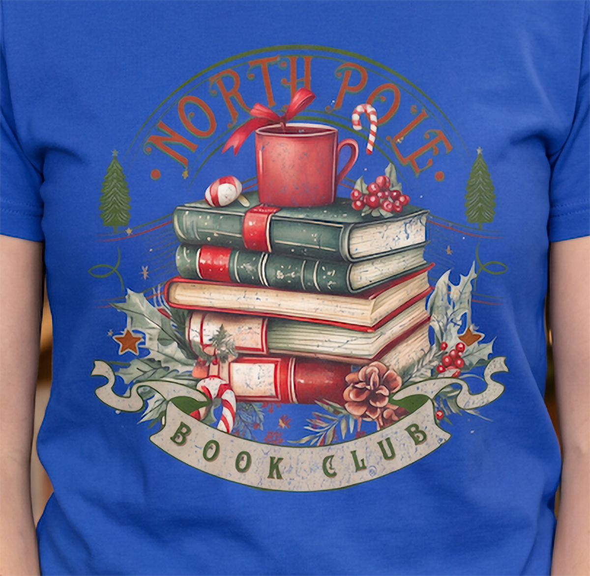 Close-up of North Pole Book Club Christmas graphic printed on blue shirt with vintage holiday reading design.
