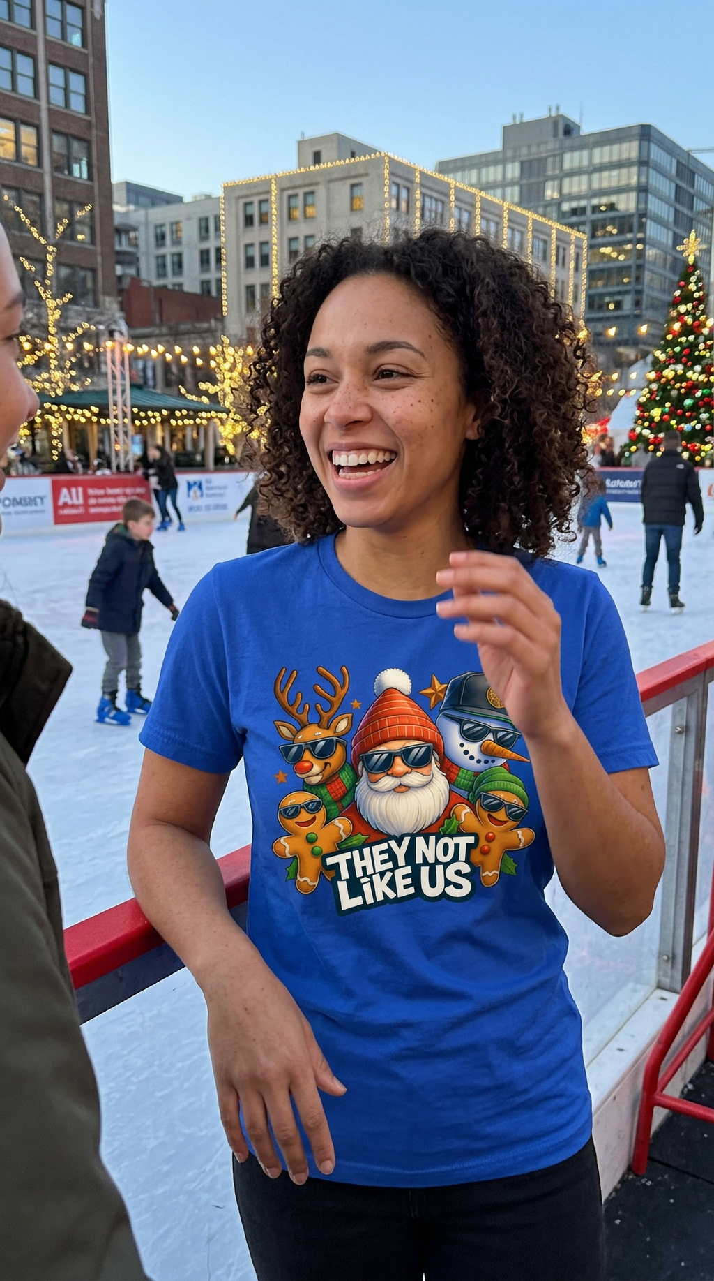 Woman wearing blue They Not Like Us Christmas graphic t-shirt while walking outdoors in a city setting.