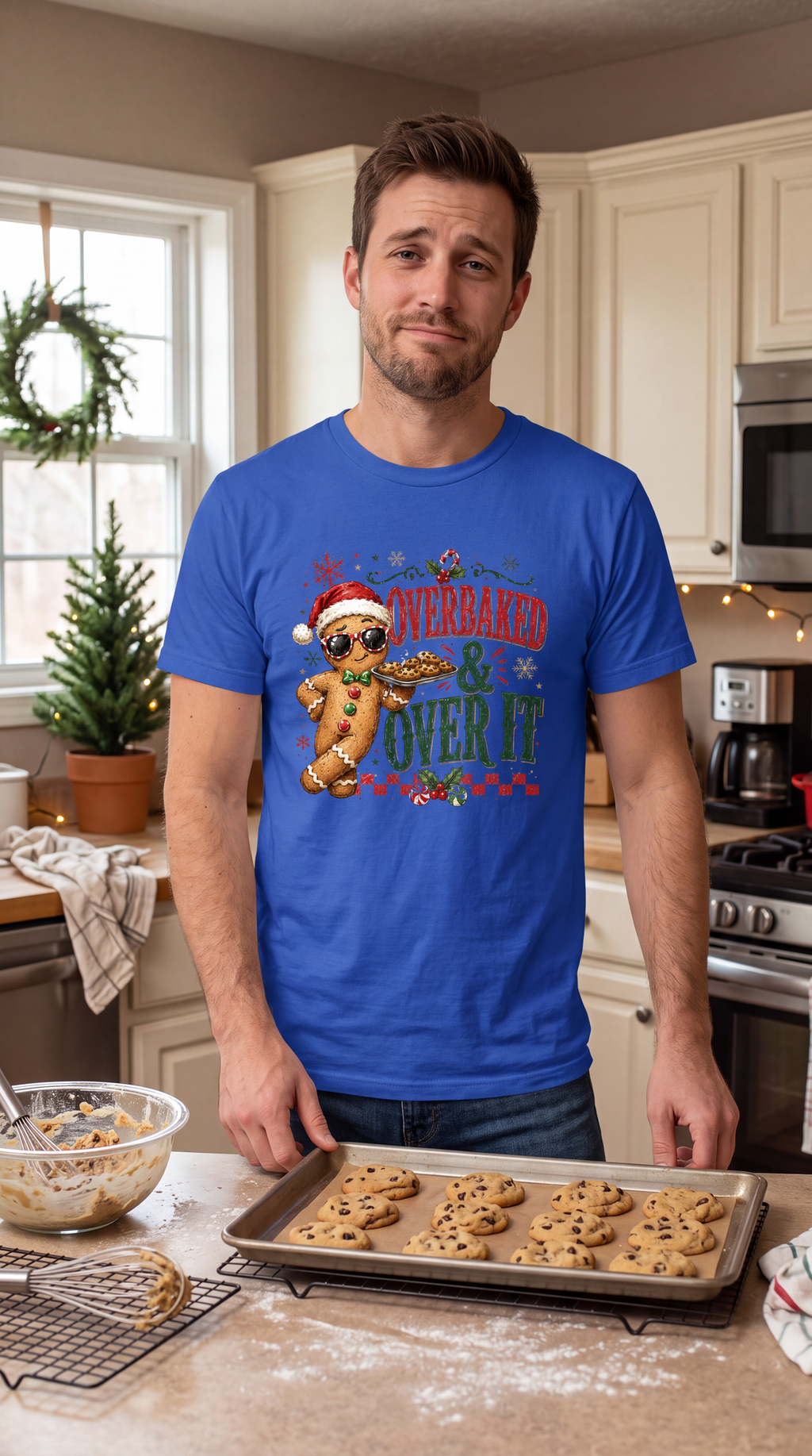 Man wearing blue Overbaked and Over It Christmas shirt with funny gingerbread holiday graphic.