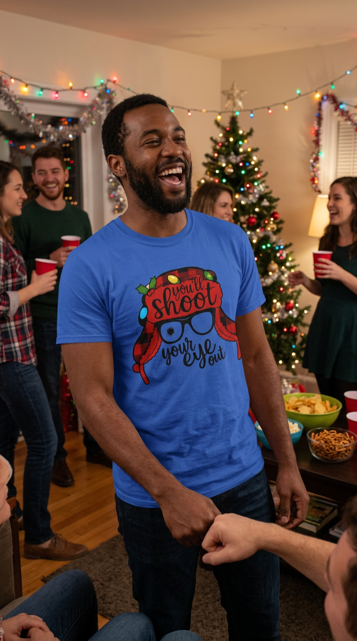 Man wearing blue funny Christmas graphic t-shirt at an indoor holiday party