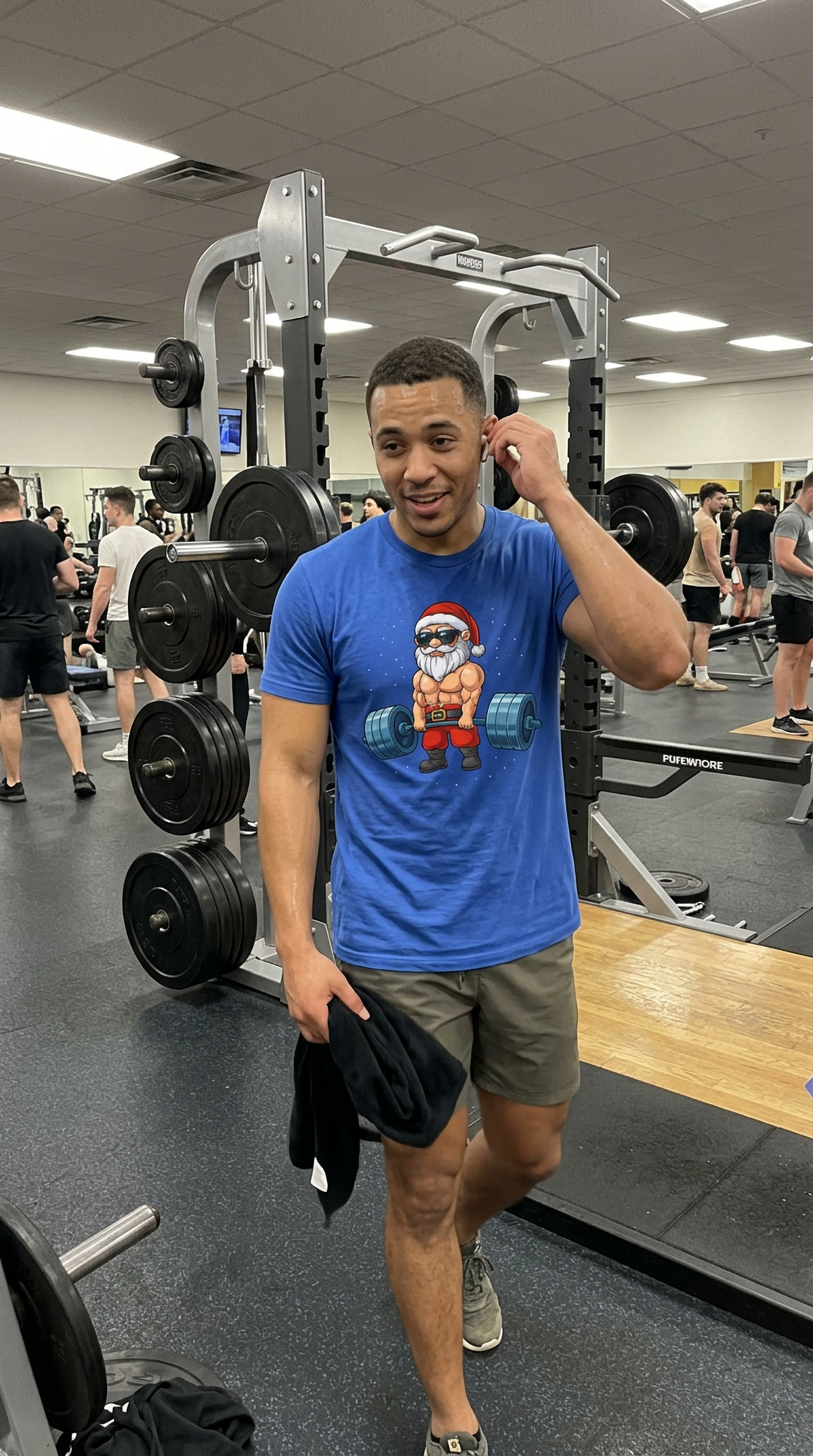 Man wearing a blue Swole Santa Christmas workout shirt at the gym featuring a muscular Santa Claus design.