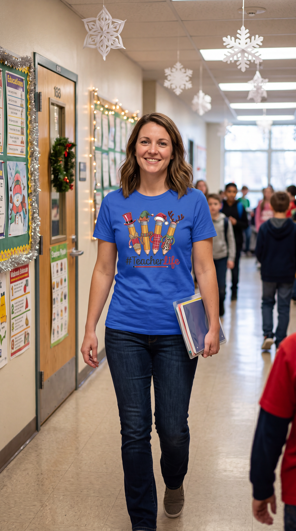 Woman wearing royal blue Teacher Life Christmas shirt with festive pencil graphic in a school hallway.