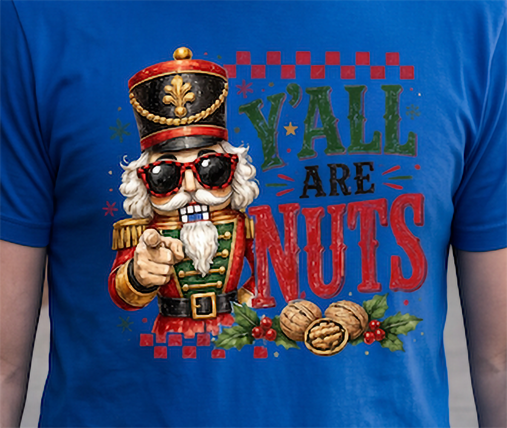 Close-up of blue Y’all Are Nuts Christmas shirt with nutcracker, walnuts, holly and holiday typography